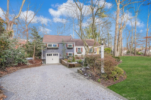 view of front of house with a garage, gravel driveway, and a front lawn