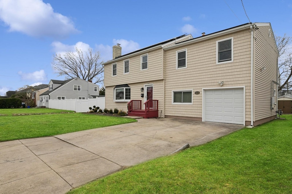 3444 Bay Front Dr, Baldwin, NY 11510 - colonial-style house with driveway, a chimney, a front yard, and fence