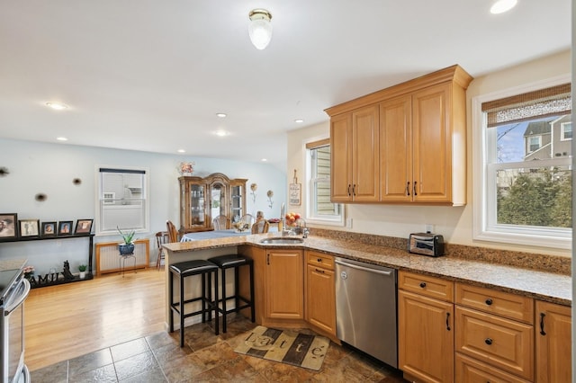 kitchen featuring a breakfast bar, a peninsula, recessed lighting, a sink, and dishwasher