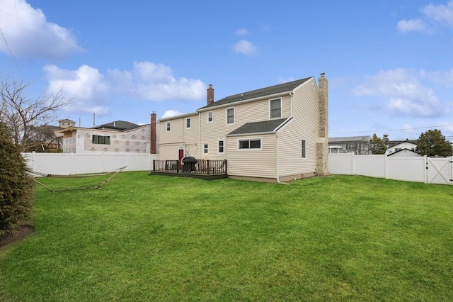 rear view of house with a yard, a deck, a fenced backyard, and a chimney