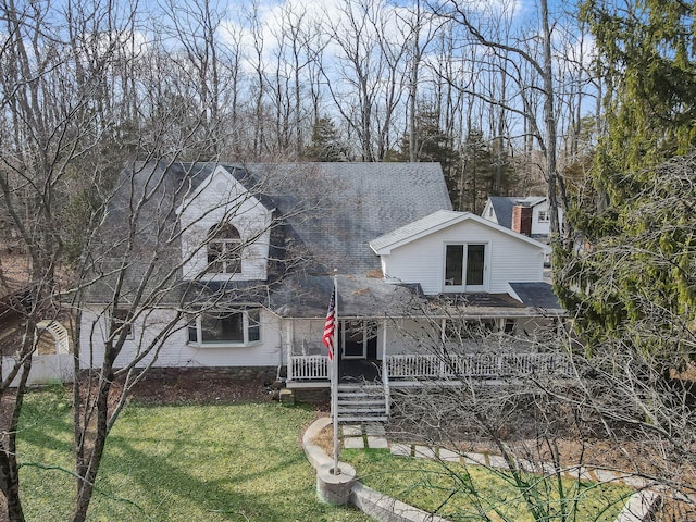 view of front of home featuring a porch, a front lawn, and roof with shingles