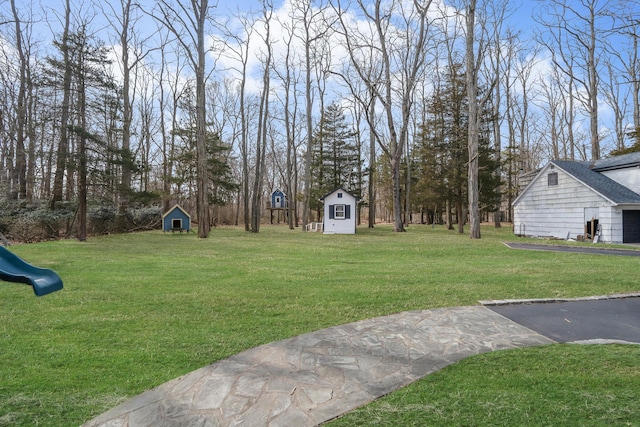 view of yard featuring a storage shed, an outdoor structure, and a playground