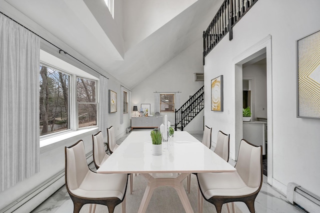 dining room featuring baseboard heating, marble finish floor, stairs, and a towering ceiling