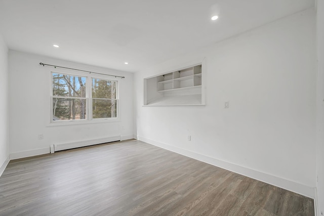 empty room with recessed lighting, a baseboard heating unit, baseboards, and wood finished floors