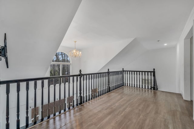 hall featuring vaulted ceiling, a notable chandelier, and wood finished floors