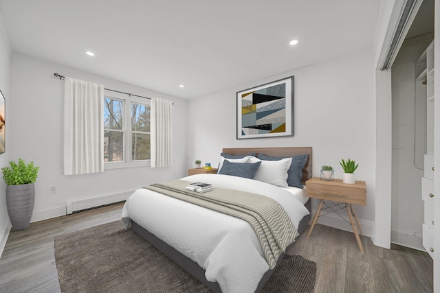 bedroom with a baseboard heating unit, recessed lighting, wood finished floors, and baseboards