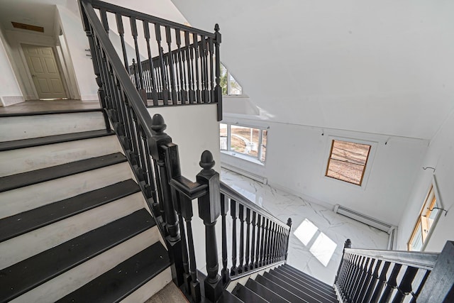 stairway featuring lofted ceiling and marble finish floor