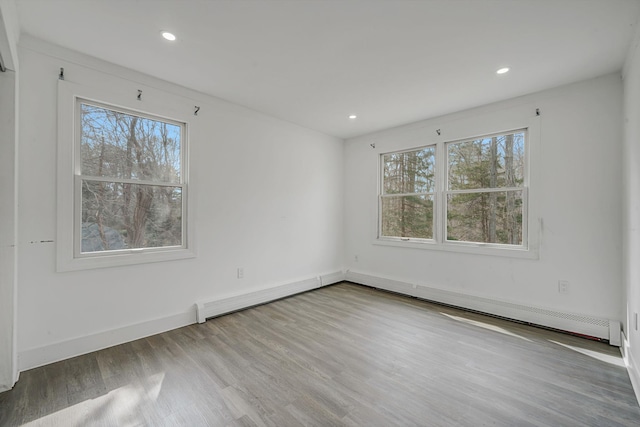 unfurnished room with recessed lighting, wood finished floors, baseboard heating, and a healthy amount of sunlight