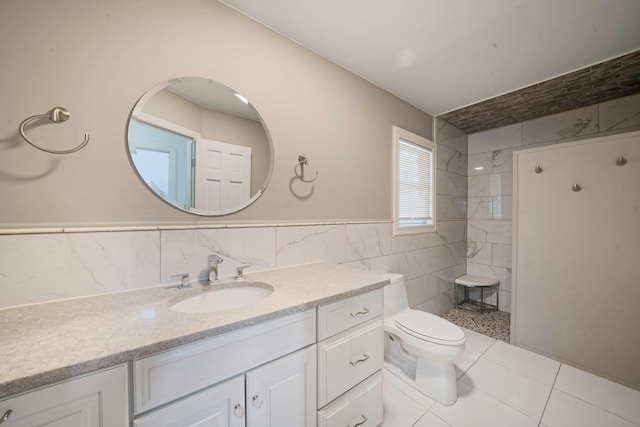 bathroom featuring vanity, tiled shower, wainscoting, tile walls, and toilet