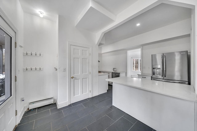 kitchen with dark tile patterned flooring, white cabinetry, appliances with stainless steel finishes, a peninsula, and baseboard heating