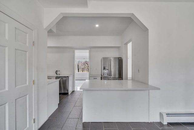 kitchen featuring a baseboard radiator, a peninsula, dark tile patterned flooring, appliances with stainless steel finishes, and white cabinetry