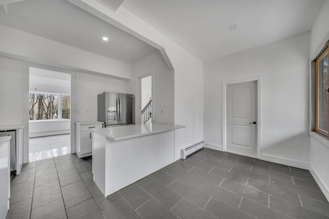 kitchen featuring a baseboard heating unit, white cabinetry, stainless steel fridge, a peninsula, and light countertops