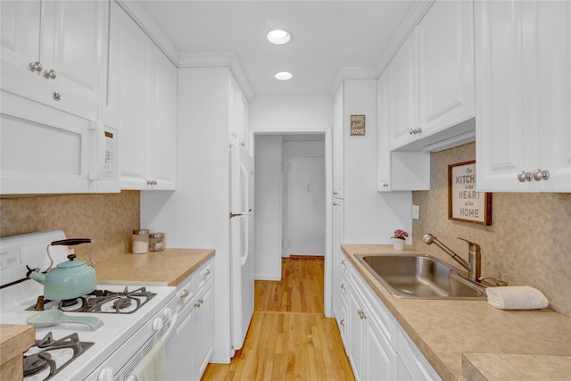 kitchen with white appliances, white cabinets, light countertops, and a sink