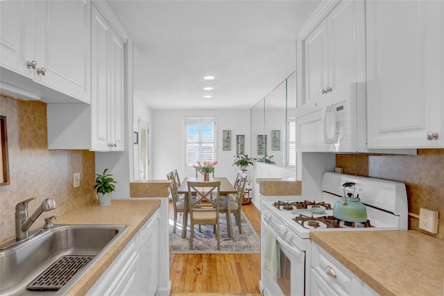 kitchen with white appliances, light countertops, light wood finished floors, and a sink