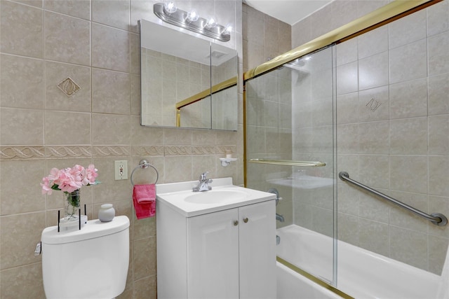 full bathroom featuring combined bath / shower with glass door, toilet, tile walls, and vanity