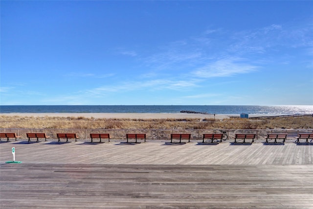 wooden deck featuring a beach view and a water view