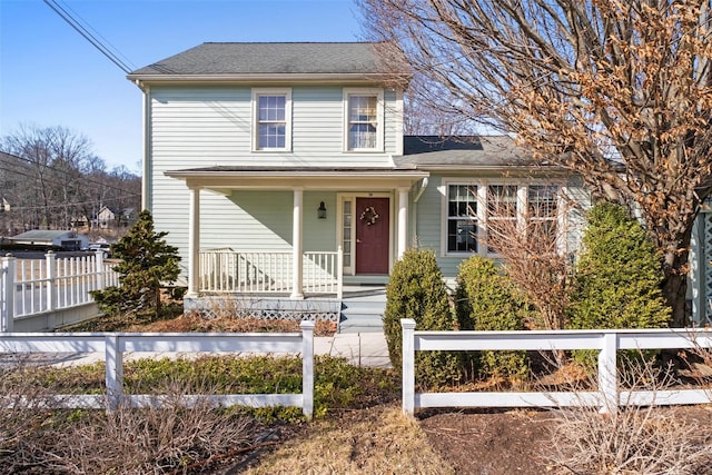 traditional-style home with a porch and a fenced front yard