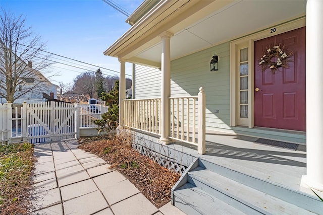 view of exterior entry with a porch and fence