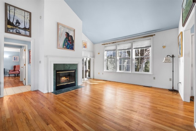 unfurnished living room featuring high vaulted ceiling, wood finished floors, and a premium fireplace