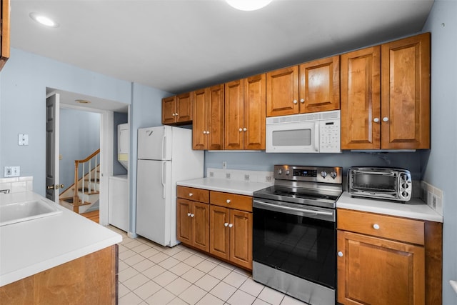 kitchen with white appliances, a toaster, light countertops, and brown cabinets