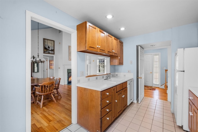 kitchen with a sink, white appliances, brown cabinets, and light countertops