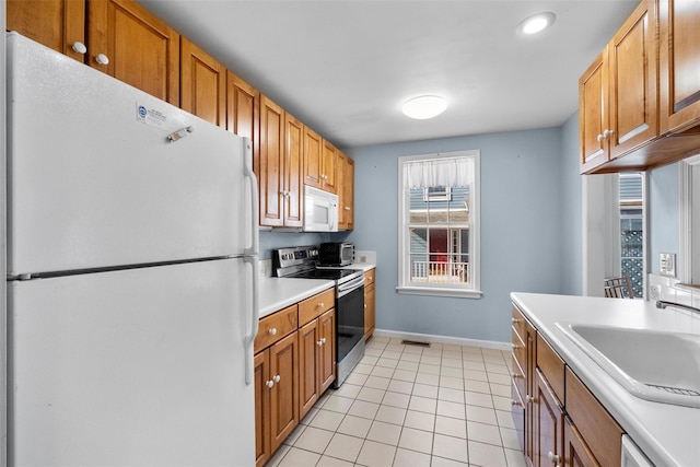 kitchen with visible vents, light countertops, light tile patterned floors, white appliances, and a sink