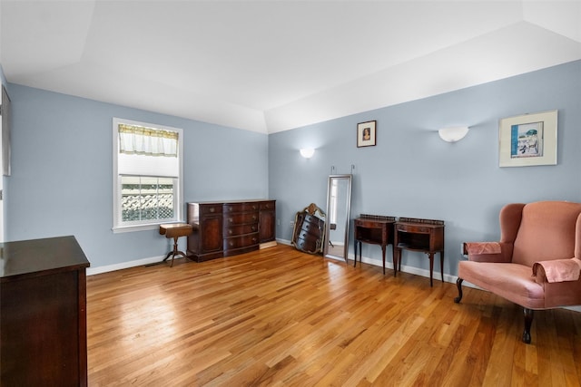 sitting room with light wood finished floors, baseboards, and vaulted ceiling