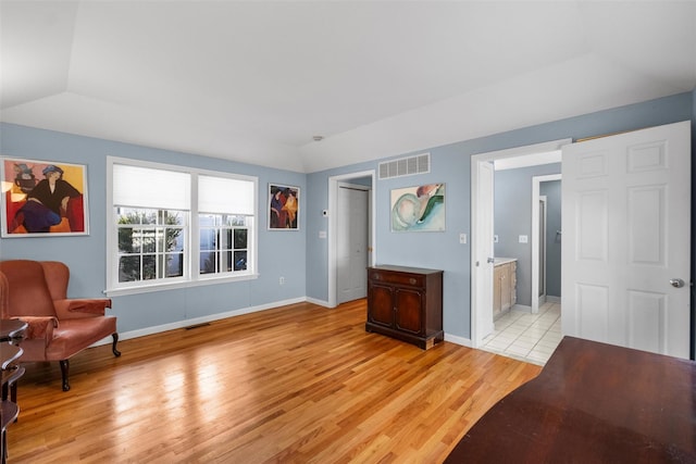 interior space featuring visible vents, lofted ceiling, baseboards, and light wood finished floors