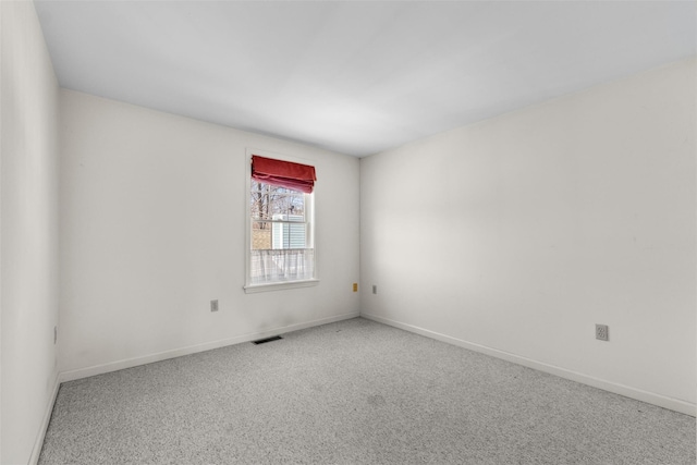 spare room featuring carpet, visible vents, and baseboards