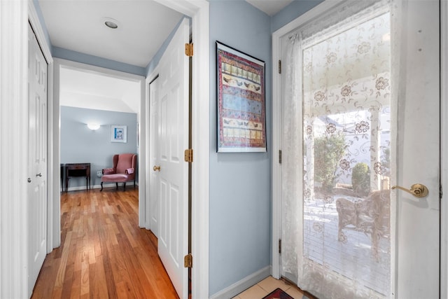 corridor featuring baseboards and light wood finished floors