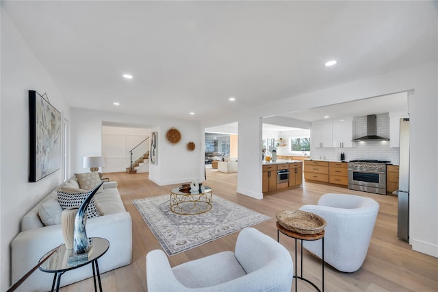 living room featuring light wood-type flooring, stairway, baseboards, and recessed lighting