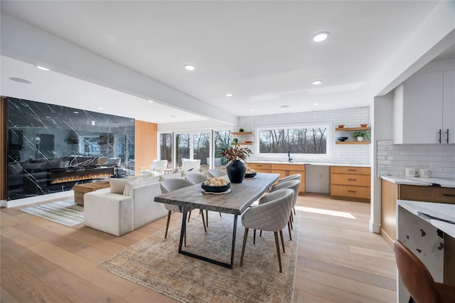 dining room with light wood finished floors, recessed lighting, and a high end fireplace