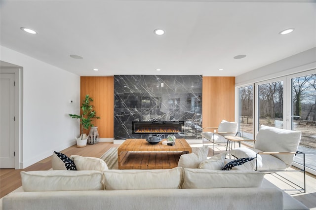 living room featuring recessed lighting, a high end fireplace, wood finished floors, and an accent wall