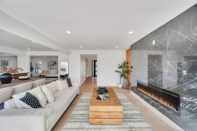 living room featuring recessed lighting, a tile fireplace, tile walls, and light wood-style floors