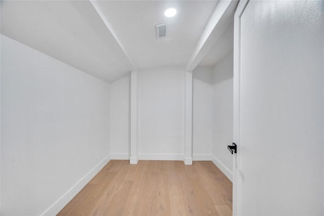 empty room featuring visible vents, baseboards, lofted ceiling, and light wood-style floors