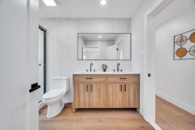 bathroom featuring double vanity, a stall shower, wood finished floors, and a sink