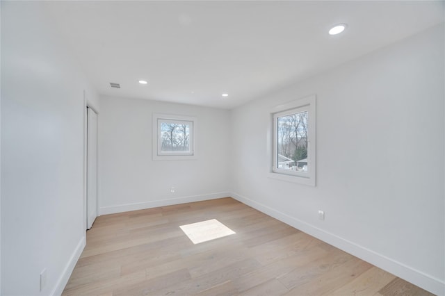 empty room with baseboards, plenty of natural light, and light wood-style flooring