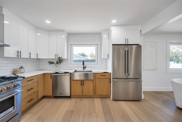 kitchen featuring a sink, stainless steel appliances, a wealth of natural light, and white cabinets