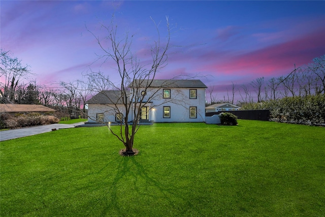 view of front of house with a lawn, concrete driveway, and fence