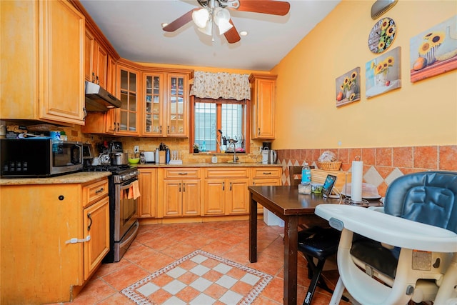 kitchen with under cabinet range hood, stainless steel appliances, a wainscoted wall, and light tile patterned floors