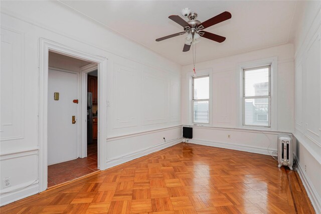 unfurnished room featuring radiator and ceiling fan