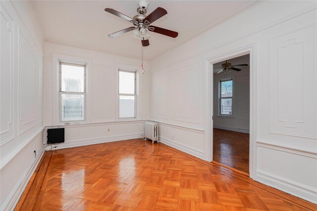 unfurnished room featuring radiator heating unit and a ceiling fan