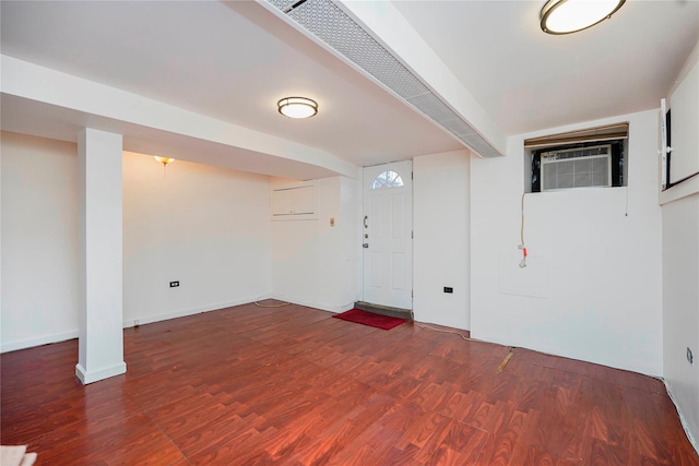 finished below grade area featuring a wall unit AC, wood finished floors, and baseboards