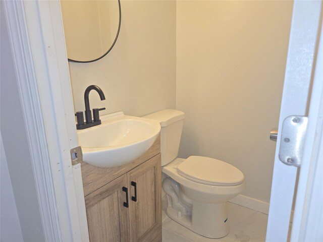 half bathroom featuring tile patterned floors, toilet, vanity, and baseboards