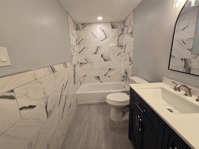 full bath with vanity, tile walls, toilet, and shower / bathing tub combination