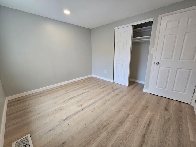 unfurnished bedroom featuring light wood finished floors, visible vents, baseboards, recessed lighting, and a closet