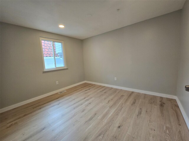 empty room with light wood-type flooring, visible vents, baseboards, and recessed lighting