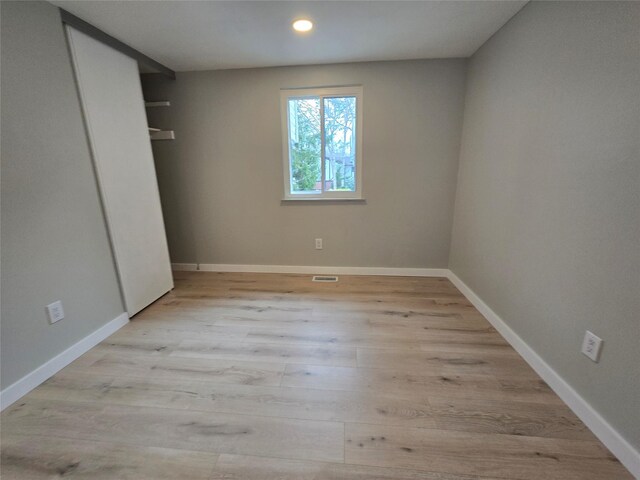 unfurnished bedroom featuring recessed lighting, wood finished floors, baseboards, and a closet