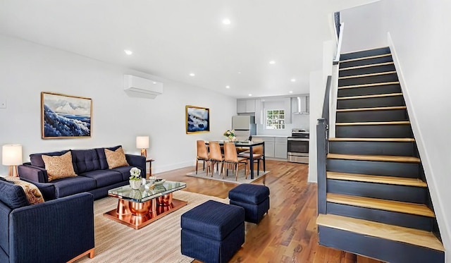 living room with stairs, a wall unit AC, recessed lighting, and light wood finished floors