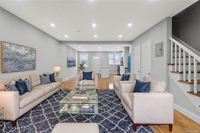 living area featuring electric panel, stairway, baseboards, and wood finished floors